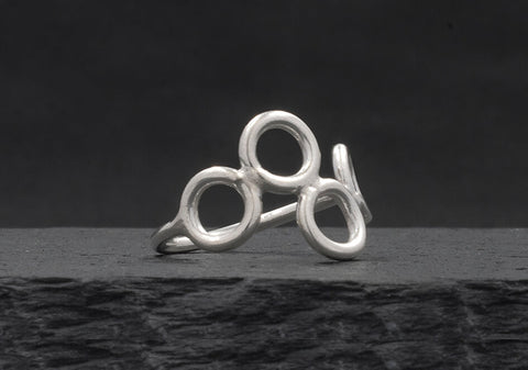 Multi-circle silver ring from Hill to Street seating on a dark grey stone over black background